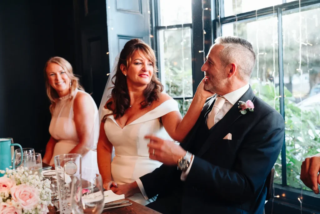 Guests laughing together during the wedding speeches at The Georgian Townhouse Norwich, the dark navy interior and fairy lights visible behind them