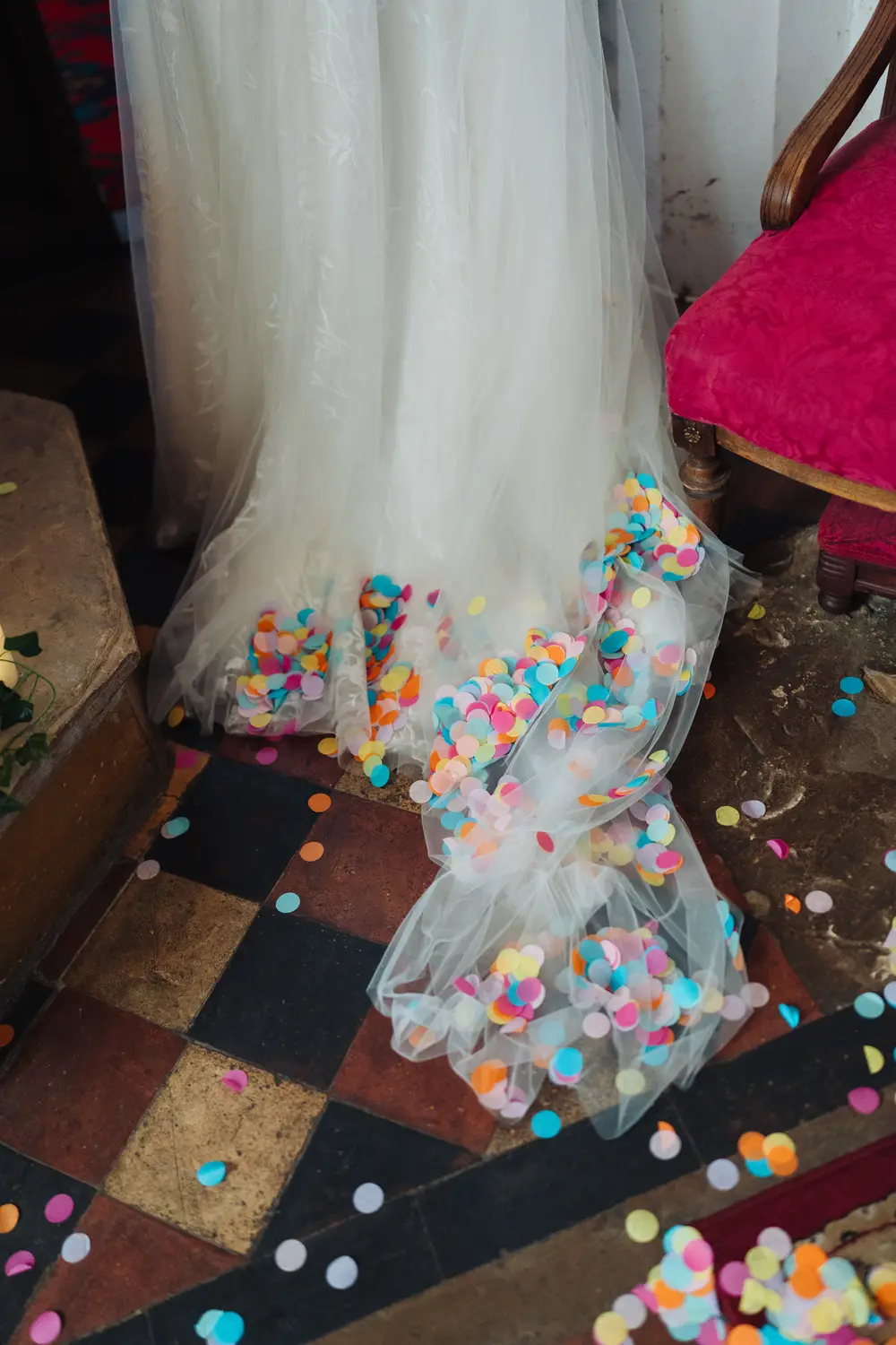 Colourful confetti scattered across the train of Sarah's wedding dress on the tiled floor inside The Flint Rooms Norwich after the indoor confetti celebration