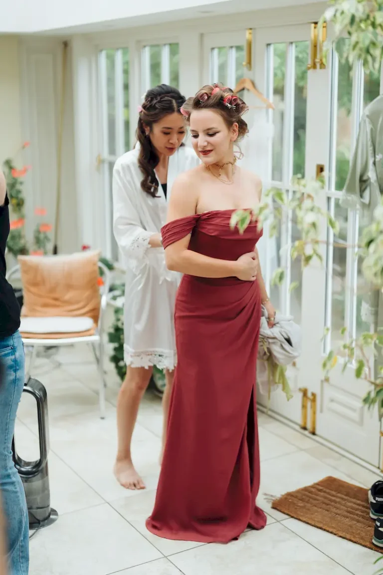 Bridesmaid in rust dress smiling in the conservatory on the morning of Antonia and Ollie’s wedding