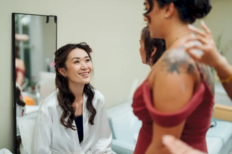 Antonia laughing with a bridesmaid in her robe while getting ready for her Bateman’s Barn wedding