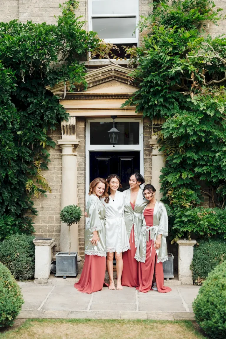 Antonia and her bridesmaids in matching robes outside the front door on the wedding morning