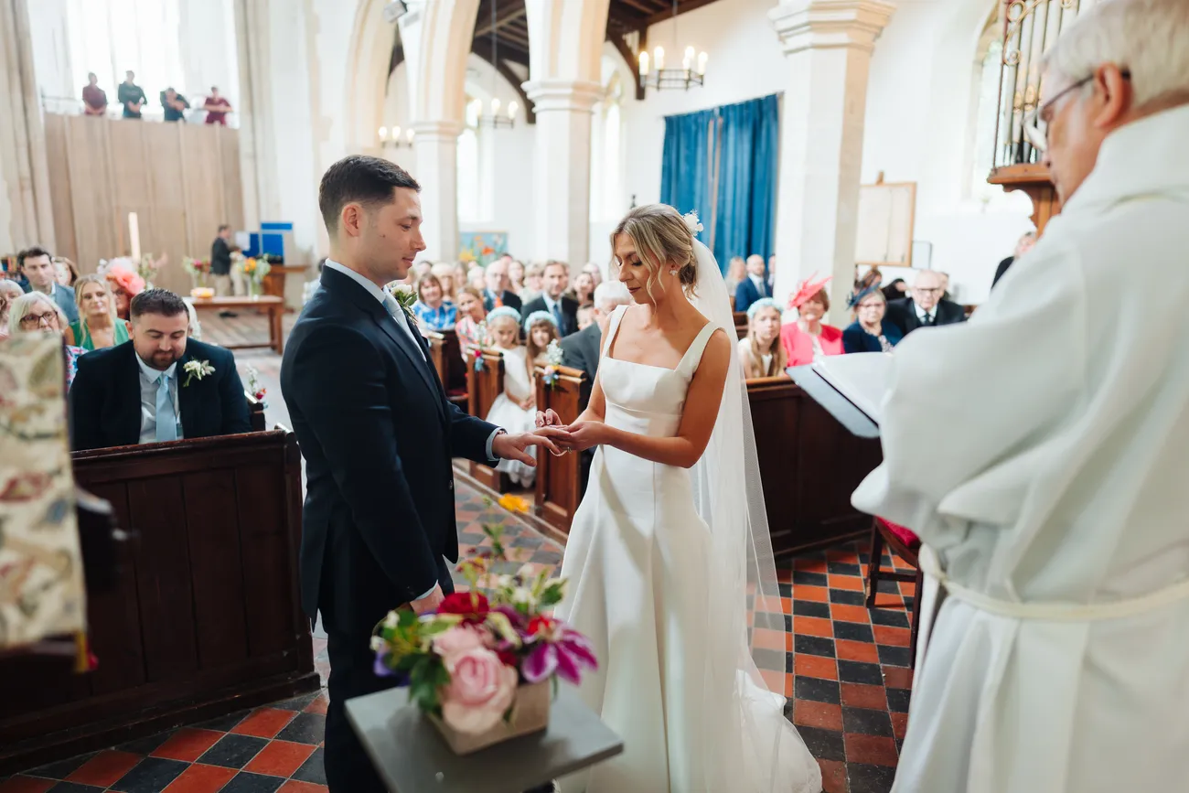 Lucy and George greeting guests outside St Andrew's Church Eaton after the ceremony