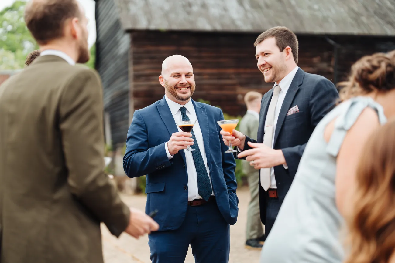 George chatting and laughing with friends at Preston Priory Barn wedding