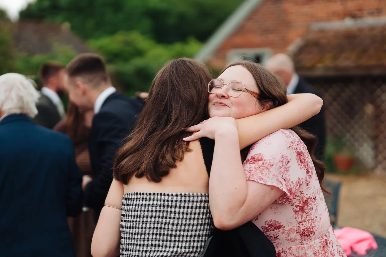 Happy couple Lucy and George surrounded by guests at Preston Priory Barn