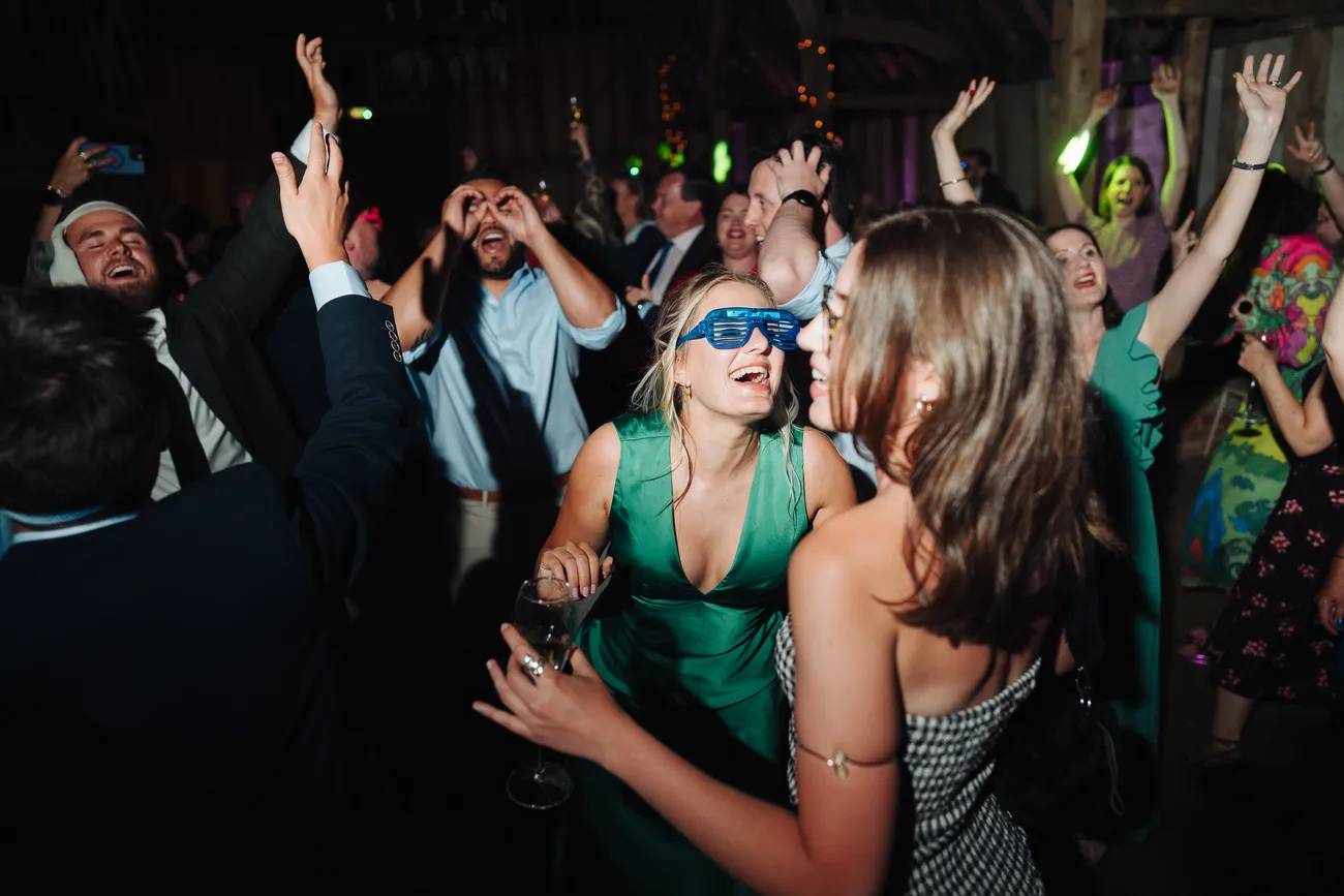 Lucy and George laughing with guests at the end of their Preston Priory Barn wedding