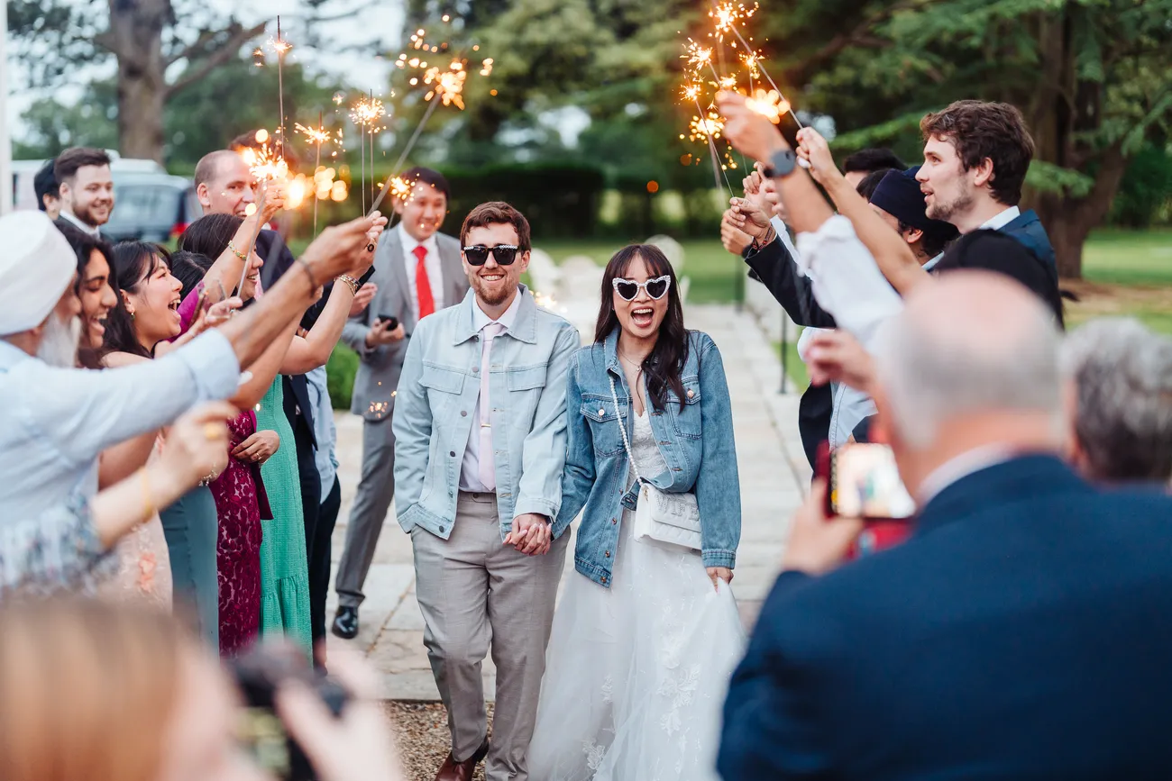 Iris and Lewis laughing with guests at the end of their Reymerston Hall wedding